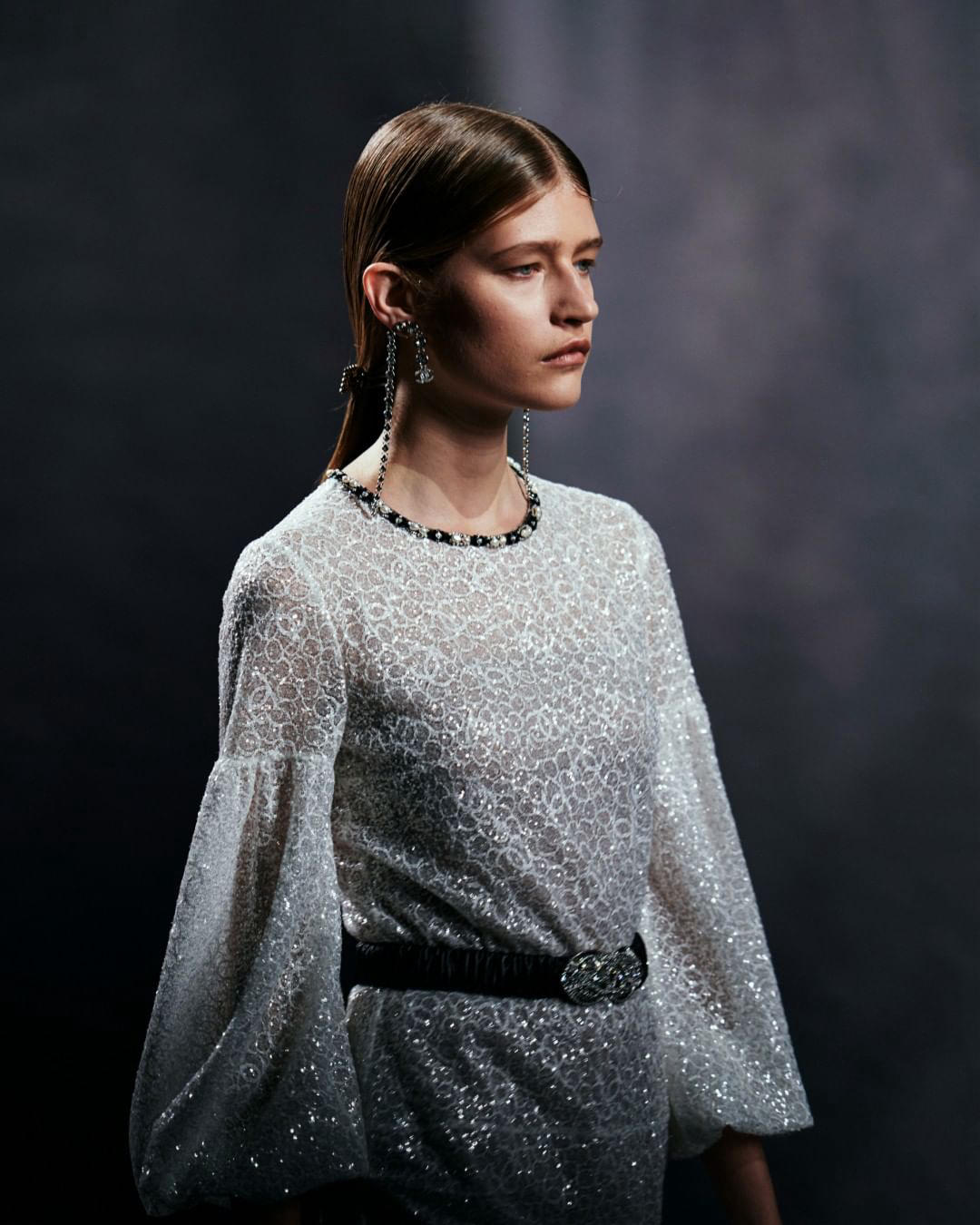 The silhouette of a flounced evening dress with floating sleeves glitters with a delicate graphic su